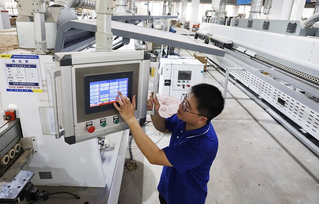 1775093813460696.jpg 4-27Y赣州 南康区搏品木工车间工人在调试水性漆机床。(杨晓明 摄).jpg